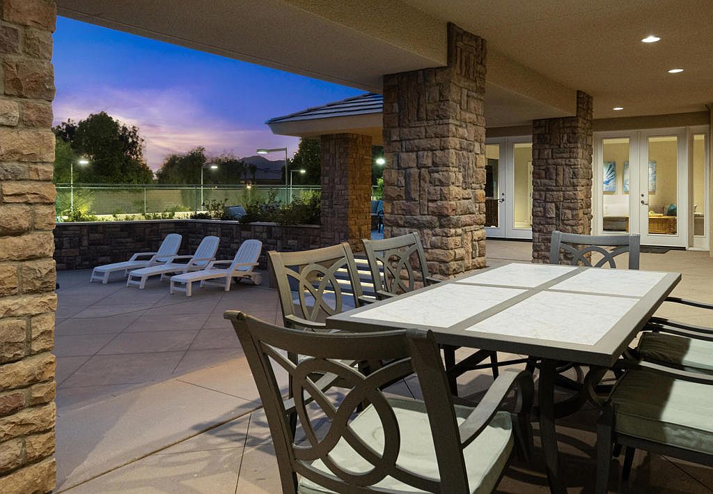 The covered patio at twilight — stone columns, marble tabletop, mountain backdrop