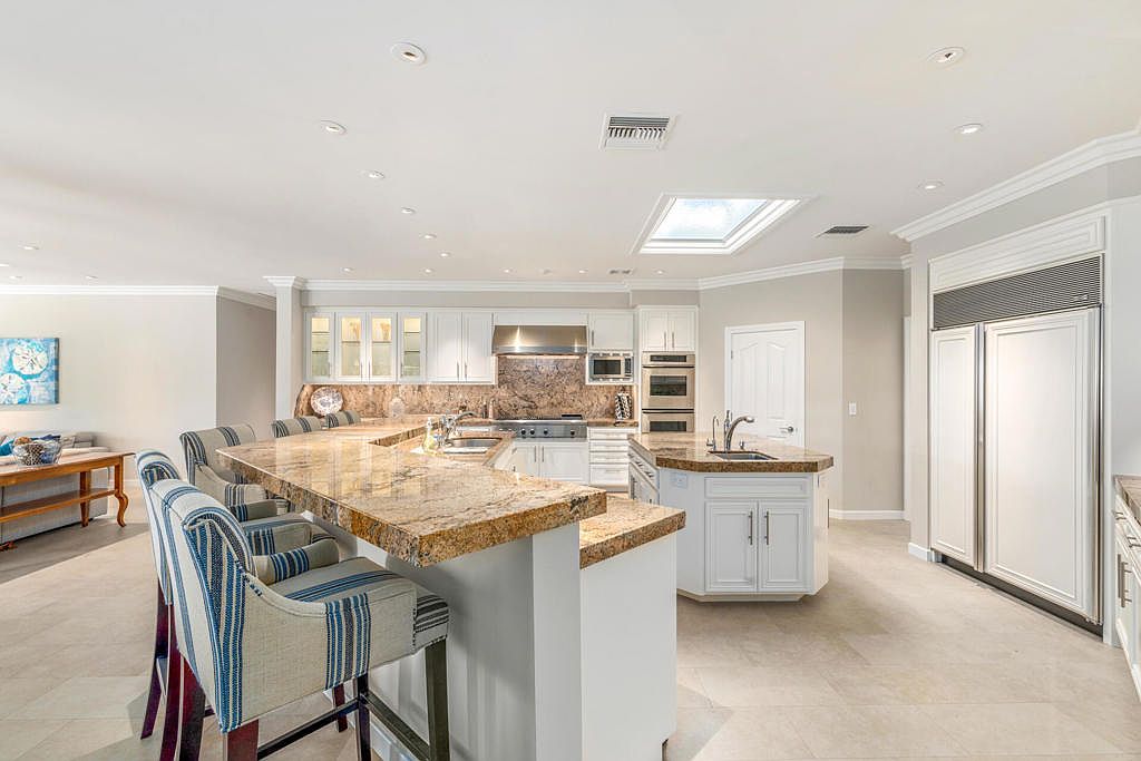 Wide kitchen view with center island and skylight, opening to the great room