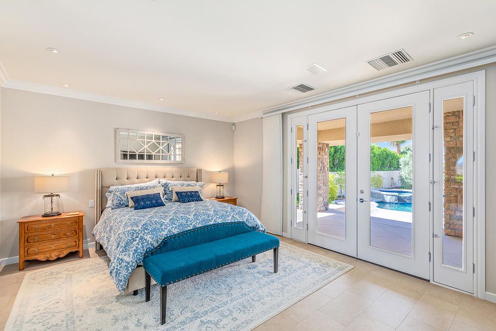 A private bedroom suite with French doors opening to the pool and mountains beyond